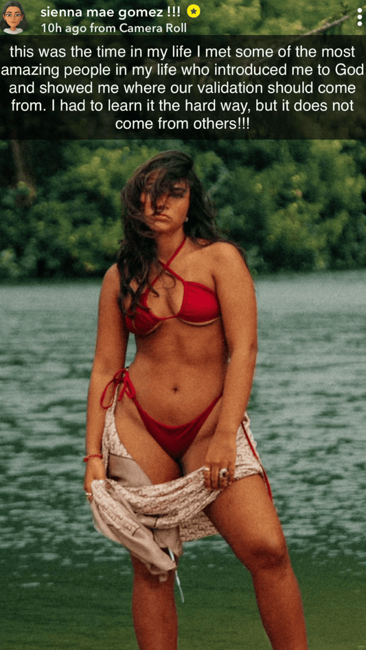 Girl posing in front of ocean and trees wearing red bikini and tan sarong