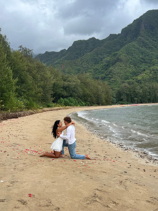 Sienna and Cole hug on the beach with mountains in the background, after he proposed to her