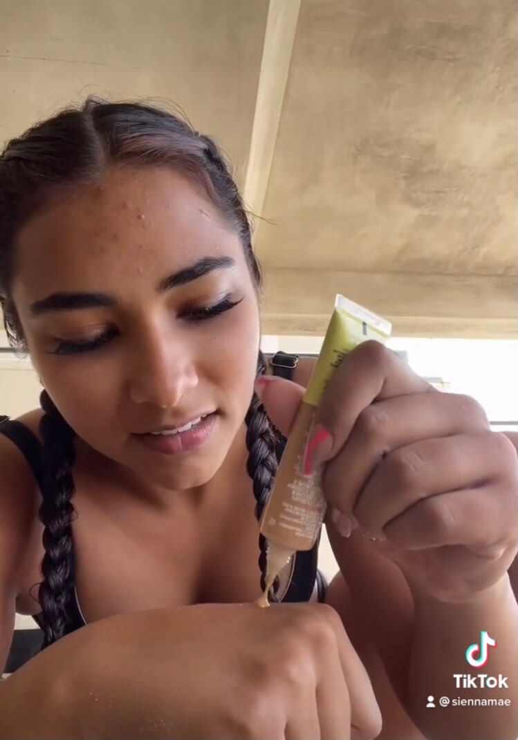 A woman putting concealer on her hand