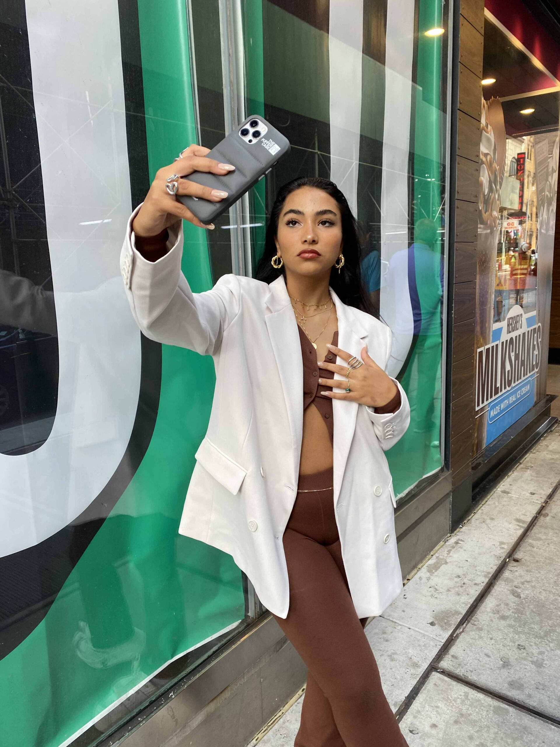 Girl taking selfie in NYC in white blazer and matching brown set underneath