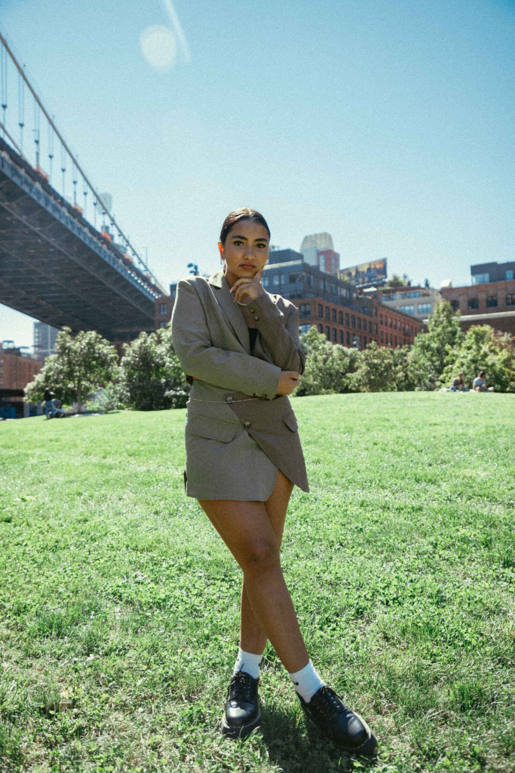 Girl standing on lawn under Brooklyn Bridge in two piece suit set