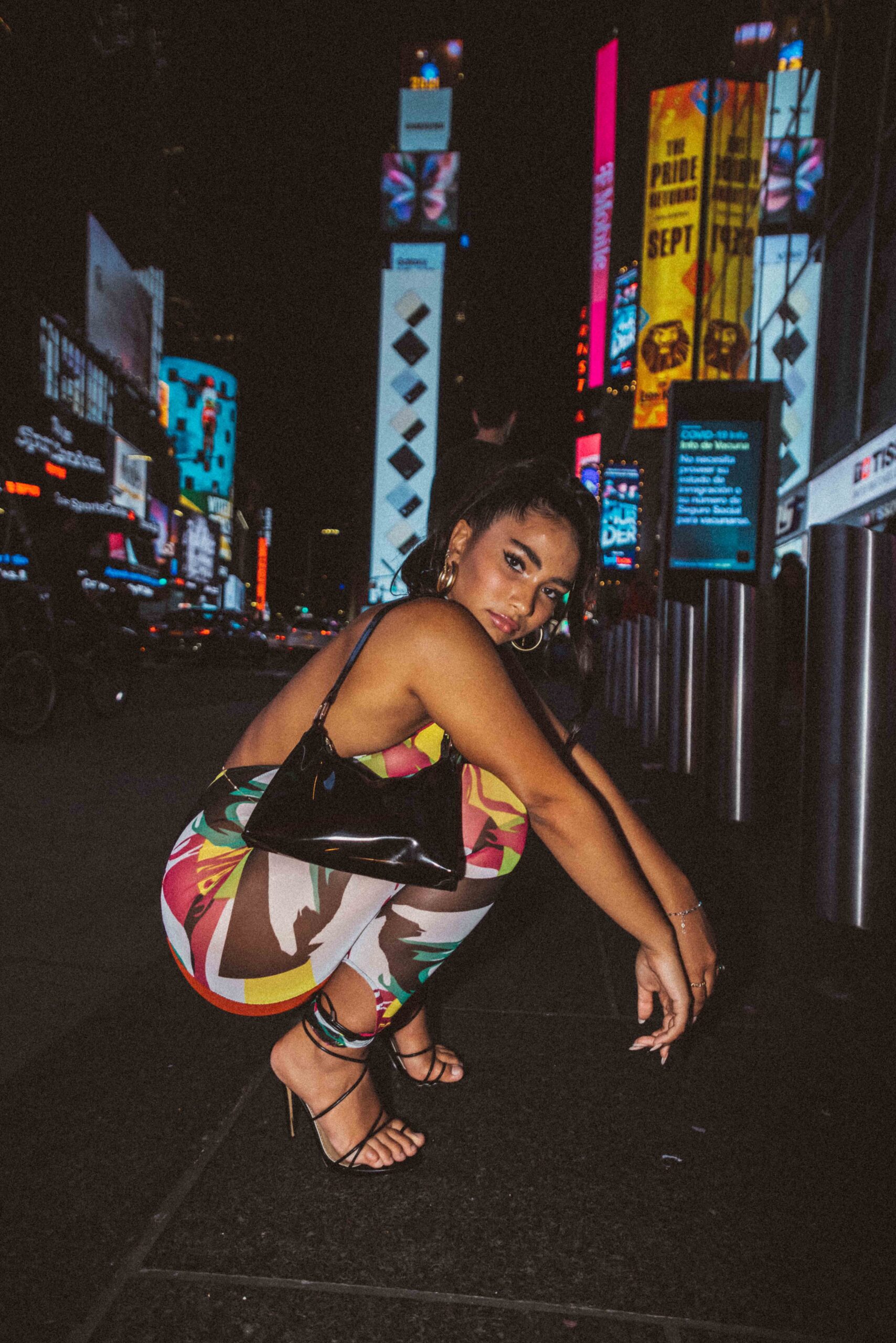 Girl kneeling in Times Square in Multicolor jumpsuit