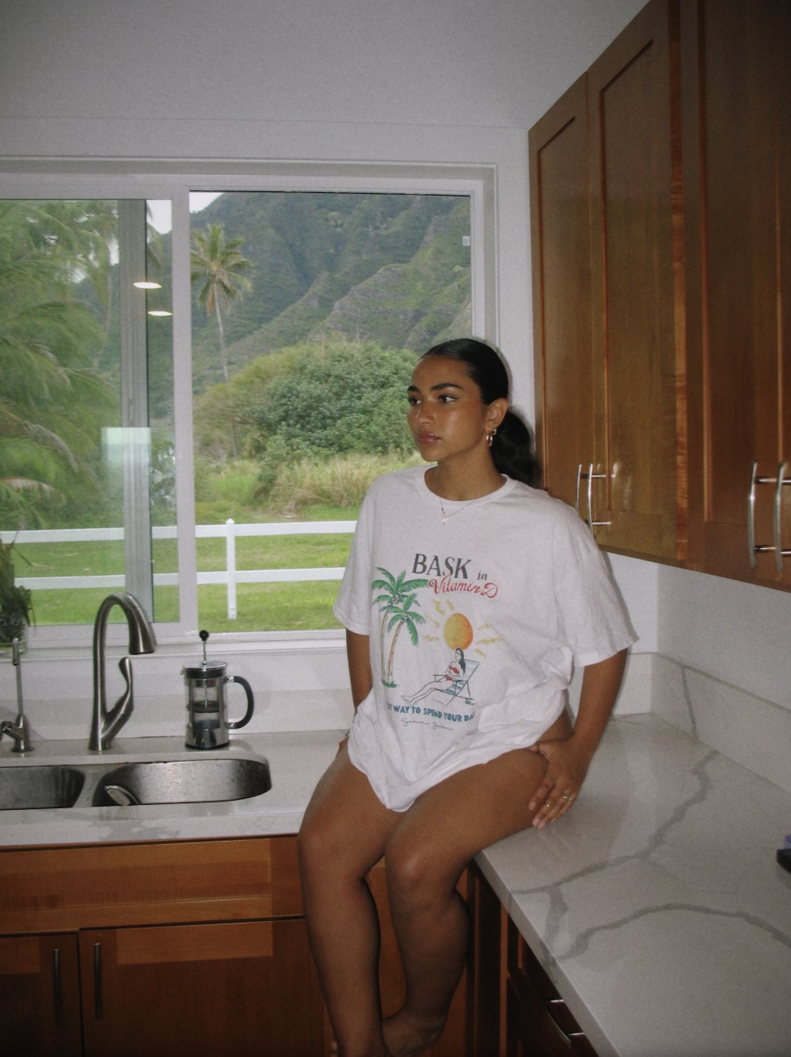 Sienna Mae Gomez sitting on kitchen counter with big tee shirt