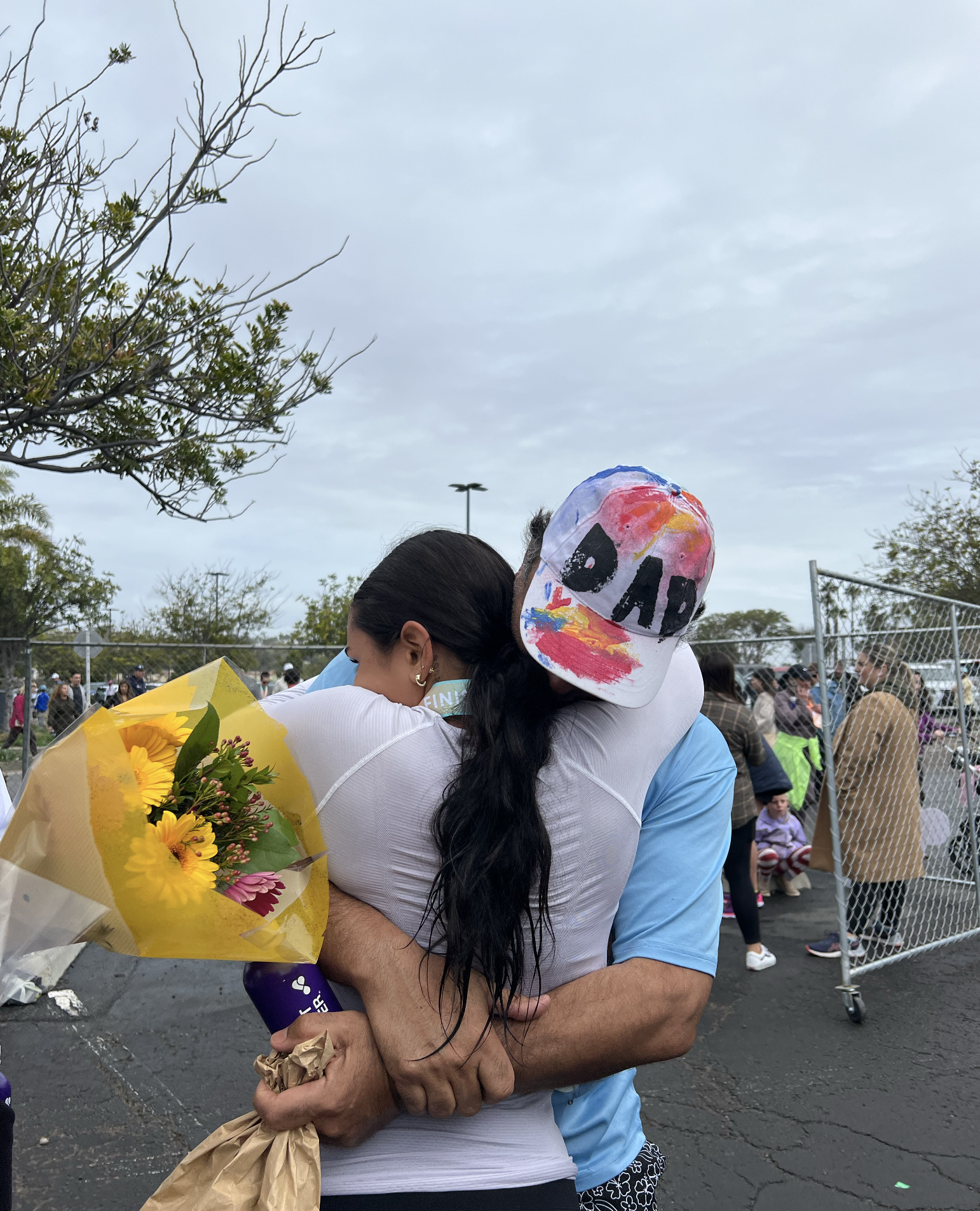 Girl hugging her father while he holds bouquet of flowers