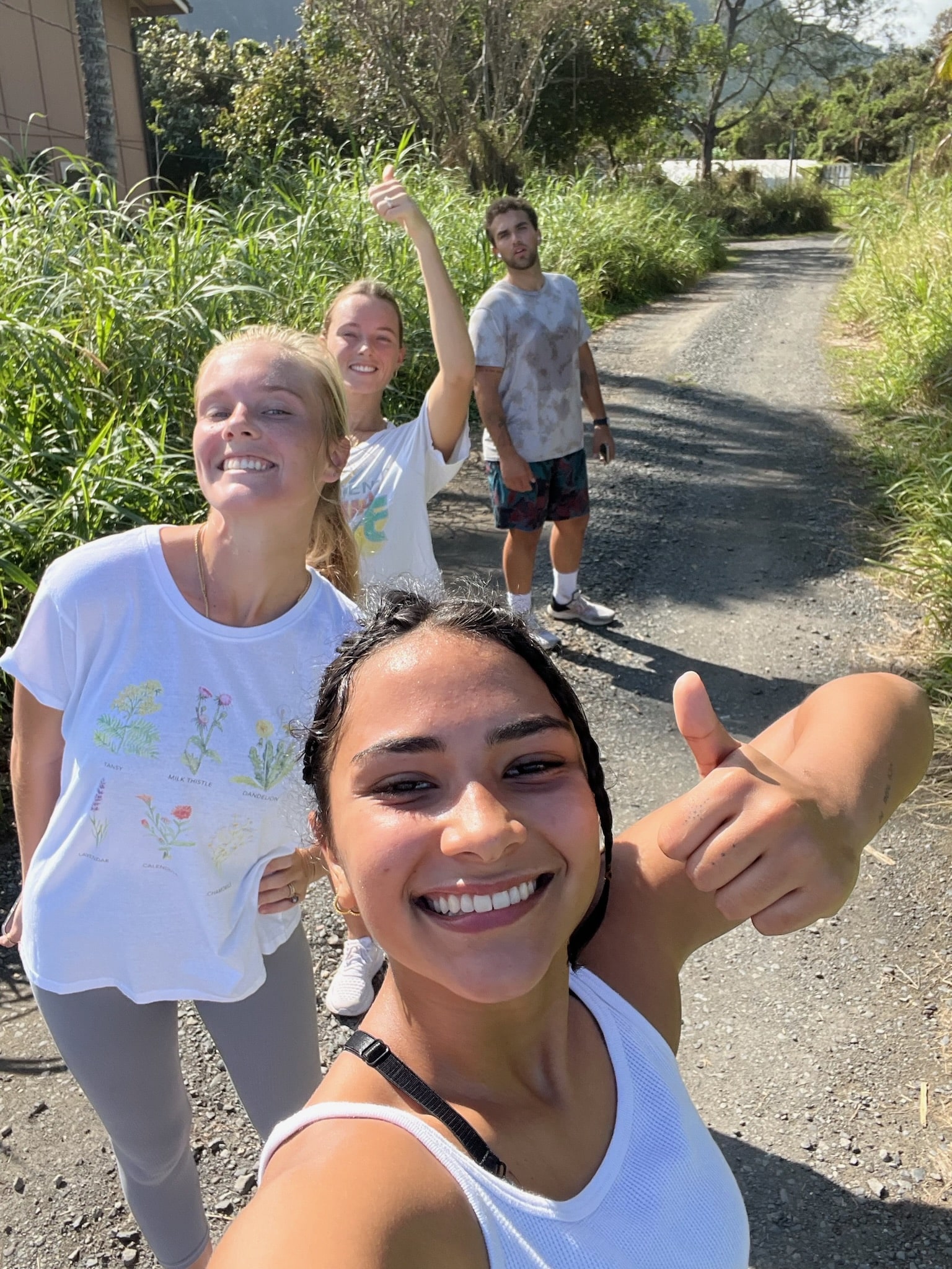 Four friends smiling into the camera giving a thumbs up while on a running trail