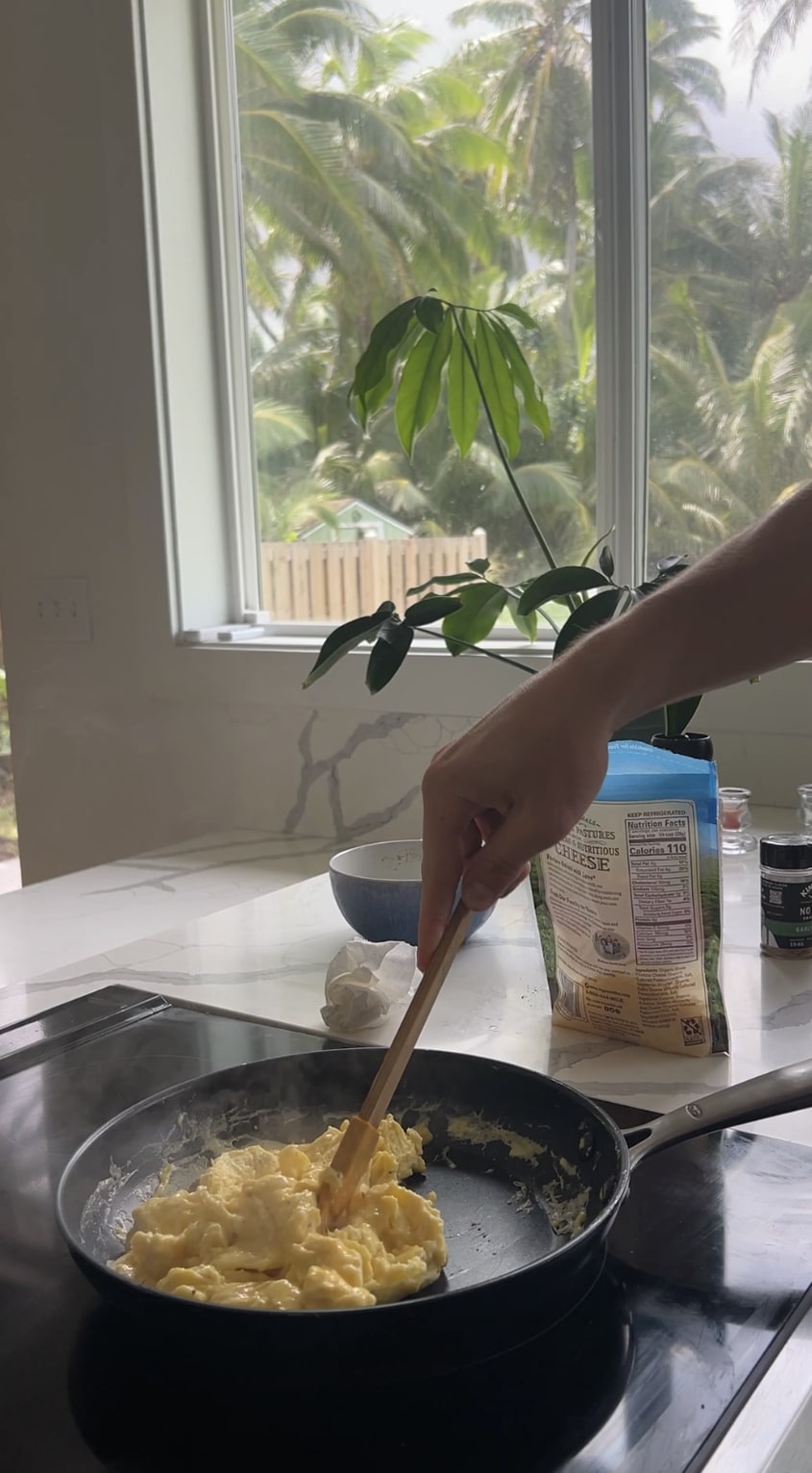 Hand stirring pan of eggs