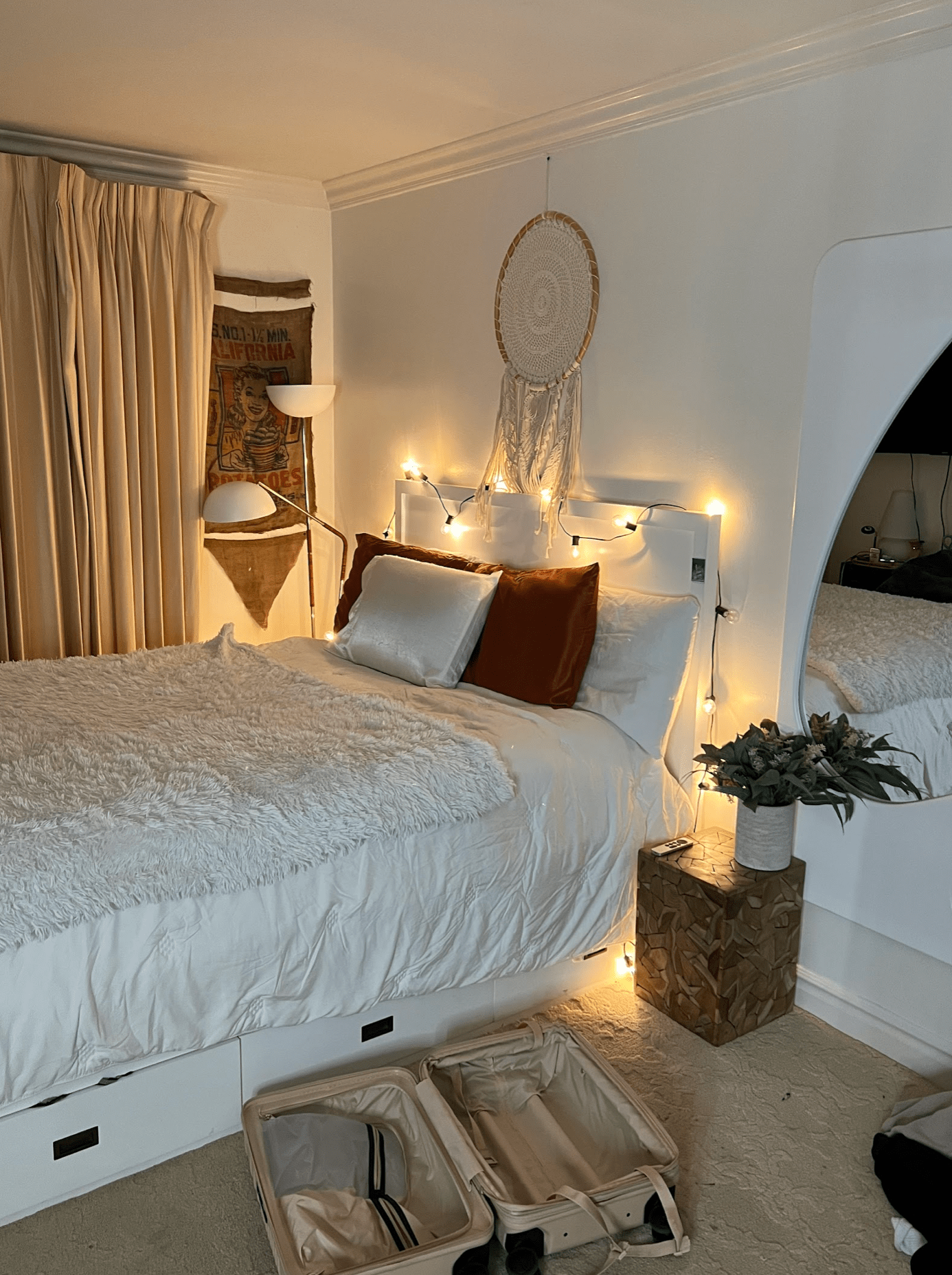 white platform bed with dream catcher and fairy lights hanging above it
