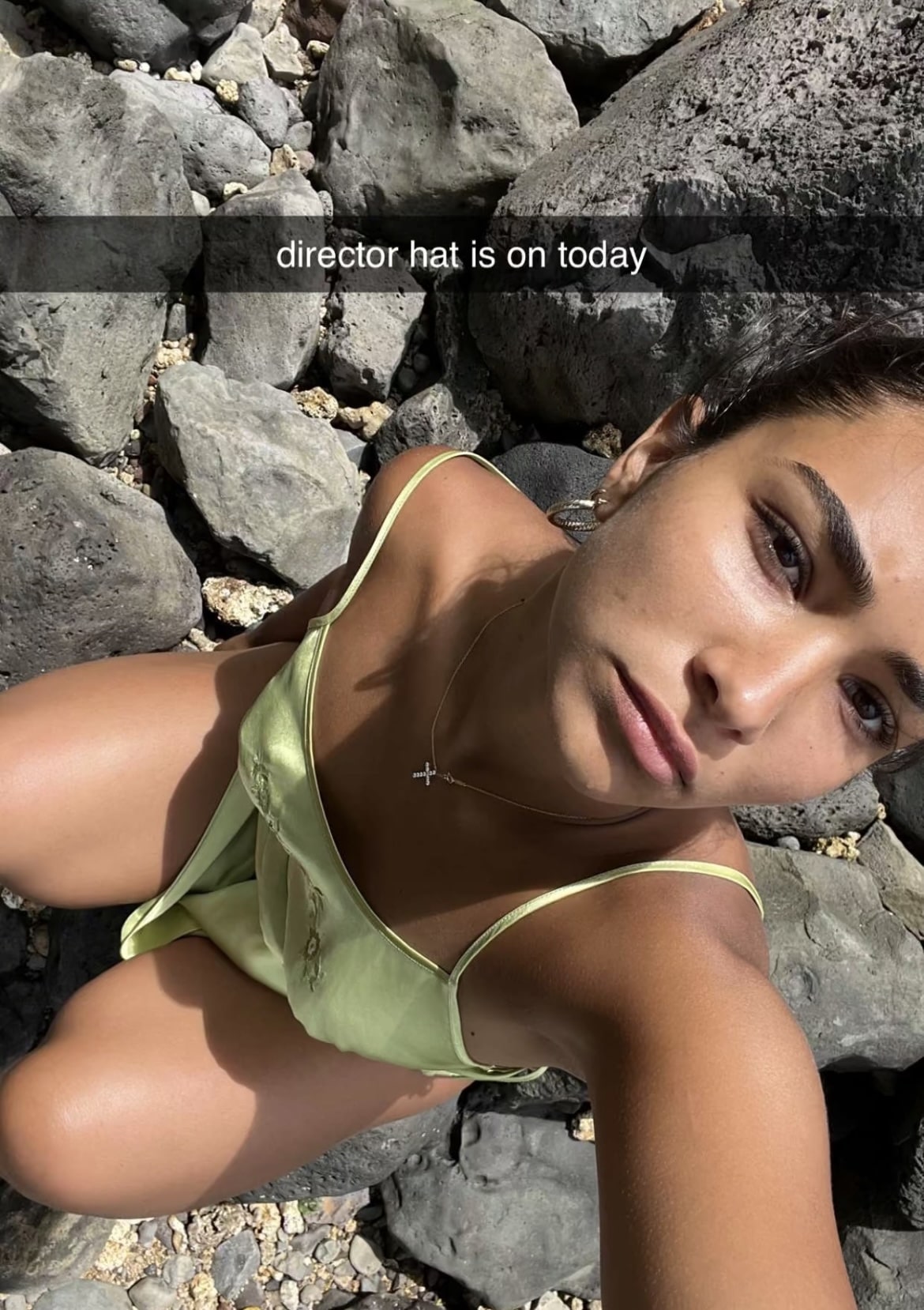Photo of girl in green dress sitting on the rocks, taking a selfie with the words, "director hat is on today" laid over the screen