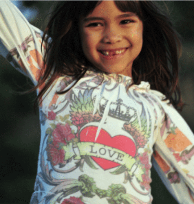 Sienna ame gomez young; young girl smiling with hands over hekadwearing Ed Hardy Kids Love tee