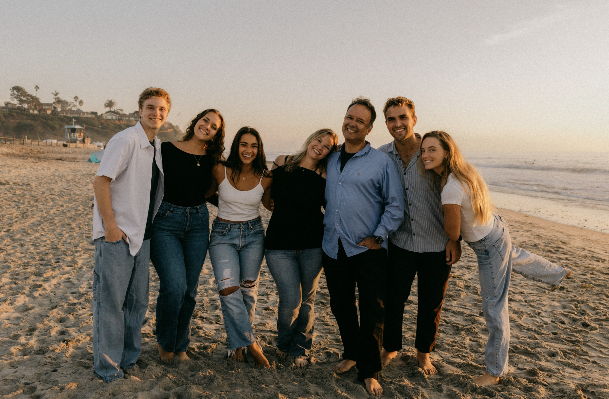 family photo of 7 standing on the beach in denim & white & denim and black