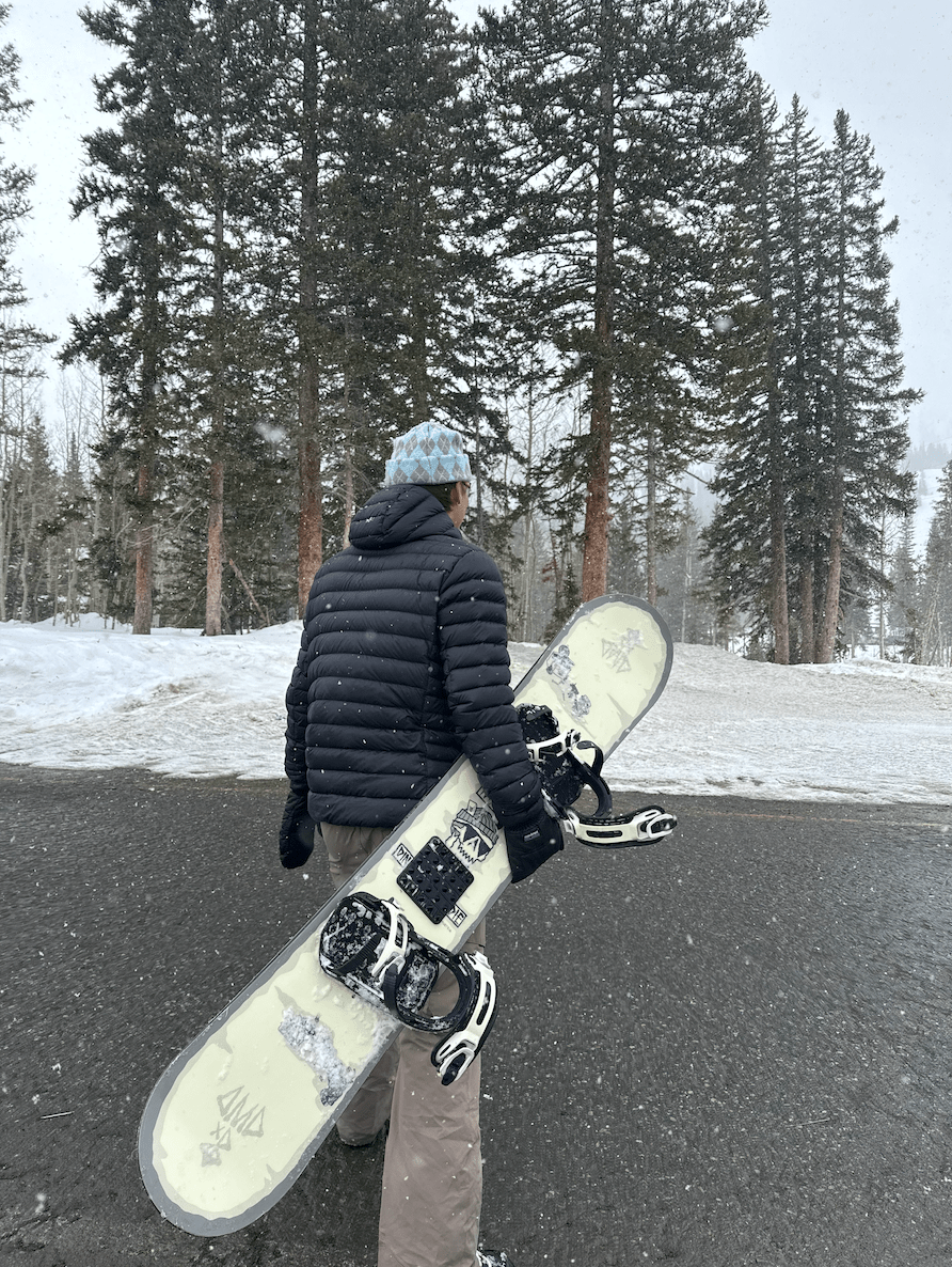 Boy facing away from the camera holding a snowboard